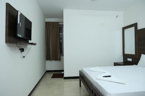 a bedroom with a bed and a flat screen tv at Hotel Aranmanai in Coimbatore