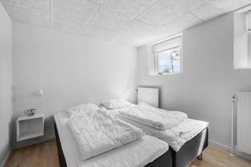 Un dormitorio con una cama con sábanas blancas y una ventana. en LN2027-Hjorring-Mollebakkevej-235-A, en Vester Vidstrup