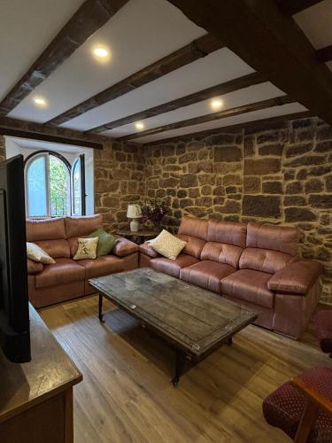 a living room with leather couches and a stone wall at Casa Dulcinea en Brañosera in Brañosera