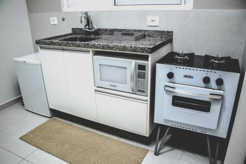 a kitchen with a stove and a microwave at Otima kitnet prox a UNIFEI c Wi-Fi e Smart TV in Itajubá