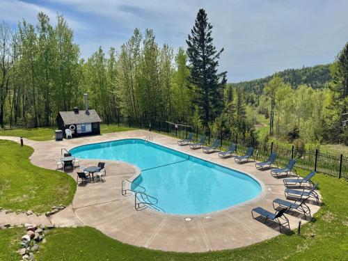 a swimming pool with lounge chairs and a house at Ski-in Ski-out Townhome at Lutsen Mountain, Pool, Hot Tub, Fitness, Sauna and more! in Lutsen