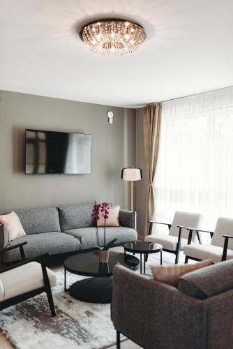 a living room with a couch and tables and a chandelier at Villa Maranga in Dombóvár