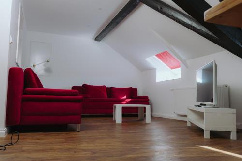 a living room with a red couch and a tv at Hotel ZweiLinden Meckenheim Bonn in Meckenheim