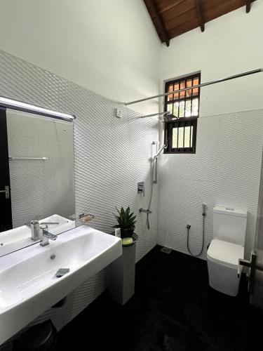 a white bathroom with a sink and a toilet at Moonbeam Villa in Colombo
