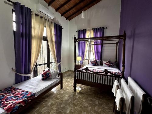two beds in a room with purple walls and windows at Moonbeam Villa in Colombo