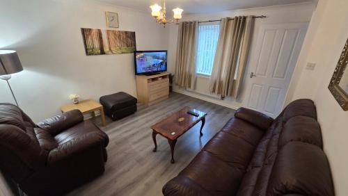 a living room with a couch and a tv at Lovely 3 Bedroom House Manchester in Manchester