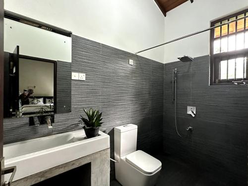 a bathroom with a toilet and a sink and a mirror at Moonbeam Villa in Colombo