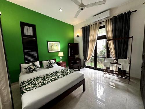 a green bedroom with a bed and a green wall at Moonbeam Villa in Colombo