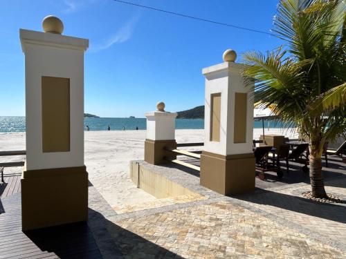 Blick auf einen Strand mit Stühlen und Palmen in der Unterkunft Golfinhos Apart hotel - apto térreo na praia com café da manhã! in Florianópolis