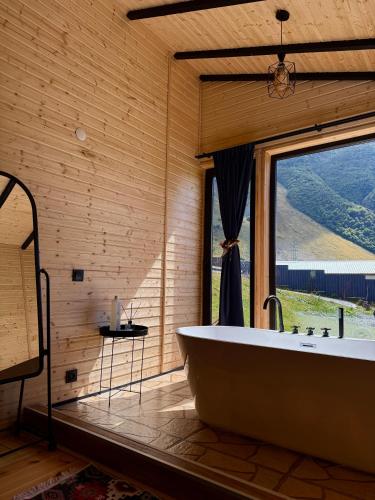 a large bath tub in a room with a window at Kazbegi Inn Cottages in Stepantsminda