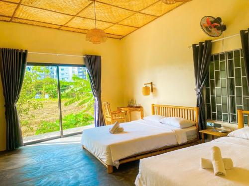 a bedroom with two beds and a large window at Ruộng Homestay Nguyên căn 5 phòng ngủ in Thôn Trường Giang