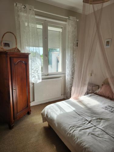una camera da letto con letto a baldacchino e finestra di Caz'Amor a Saint-Sylvestre-sur-Lot