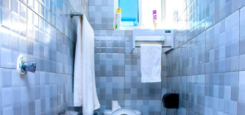a blue tiled bathroom with a toilet and a towel at Salsa Holiday apartments in Diani Beach