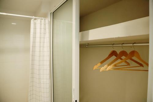 a bathroom with a shower curtain and wooden hangers at Full Stop Pool Villa Don Mueang in Lak Si