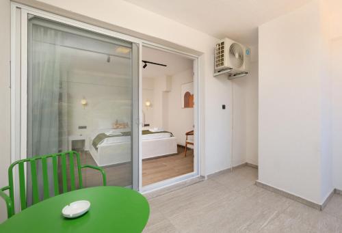 a room with a green table and a bedroom at Tütsü Pension & Suites in Eskiömerler