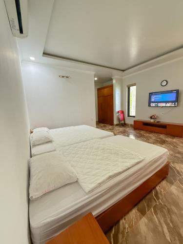 a bedroom with a large bed with a tv on the wall at Phuong Linh Beach Villa in Nha Trang
