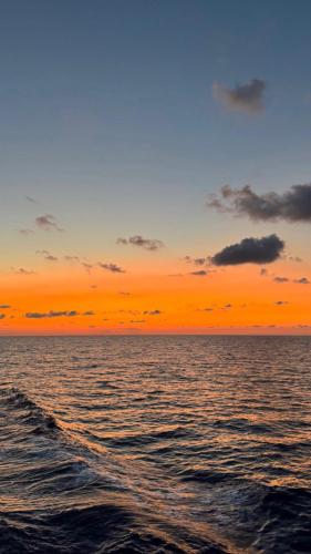an orange sunset over the ocean with waves at Sifnos Blue Horizon House - Endless Blue in Apollonia