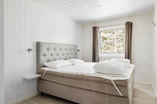 ein Bett in einem weißen Zimmer mit einem Fenster in der Unterkunft 3716 Nexø - Granvej 12 in Snogebæk