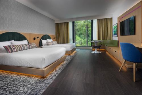 a hotel room with two beds and a desk at The Artful Way Hotel in Asheville