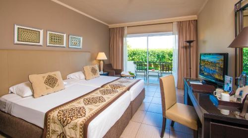 a hotel room with a bed and a desk and a television at JAZ Fanara Resort in Sharm El Sheikh