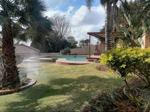 a backyard with a swimming pool and palm trees at Die Heuwel Luxury Suites in Witbank