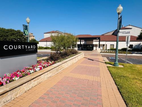 a walkway in front of a building with a sign and flowers at Courtyard by Marriott Waco in Waco
