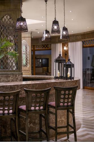 a kitchen with a bar with three chairs and pendant lights at JAZ Fanara Resort in Sharm El Sheikh