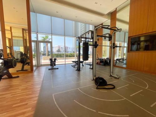 a gym with tread machines and a large window at Hive Stayz - 1 Bedroom in Catamaran Tower in Sanābis