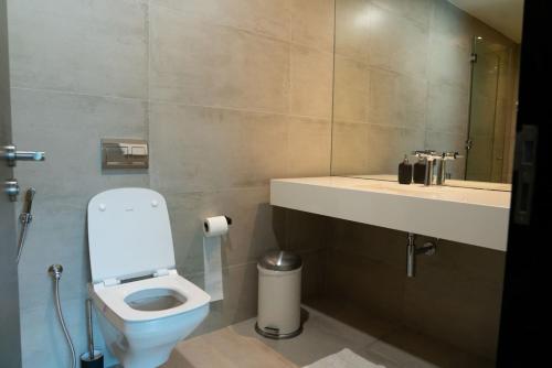 a bathroom with a toilet and a sink and a mirror at Hive Stayz - 1 Bedroom Canal Harbor Row in Manama