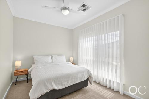 a white bedroom with a bed and a large window at Boomer View in Port Elliot