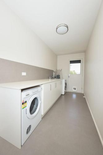 a white laundry room with a washer and dryer at Aireys Nest in Aireys Inlet