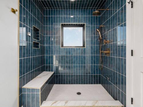 a blue tiled bathroom with a shower with a bench at High End New Build, Rooftop Hot Tub, City Views in Milo