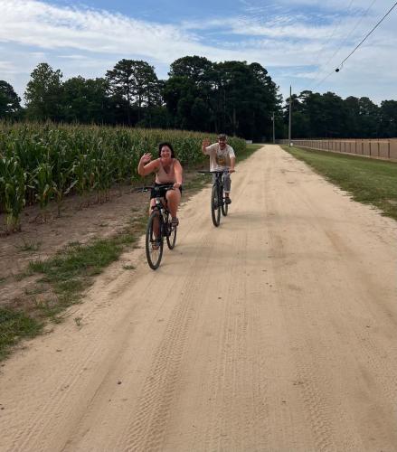 a man and a woman riding bikes down a dirt road at Sweet 1BDR Farm Cottage with Fire Pit and Creek View in Hacksneck