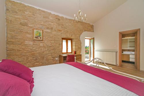 une chambre avec un grand lit et un mur en pierre dans l'établissement Villa Marija in Pekici (Haus für 8-10 Personen), à Svetvinčenat