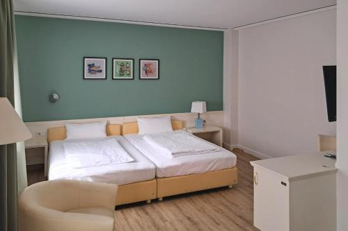 a bedroom with a bed and a chair in it at Garner Hotel Aschaffenburg Post by IHG in Aschaffenburg