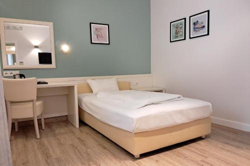 a bedroom with a bed and a desk and a mirror at Garner Hotel Aschaffenburg Post by IHG in Aschaffenburg