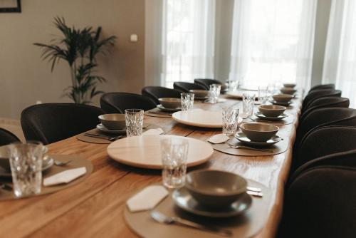 a long table with black chairs and plates and glasses at Villa Maranga in Dombóvár