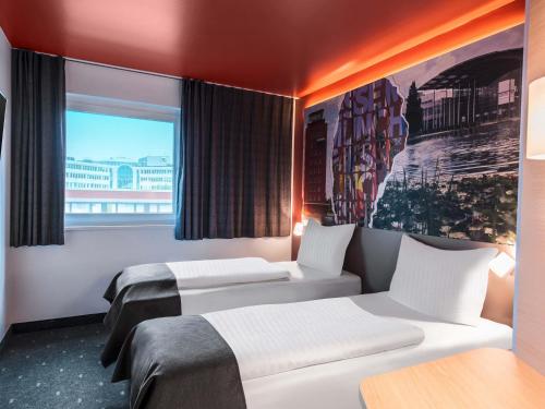 two beds in a room with a window at B&B HOTEL München-Messe in Aschheim