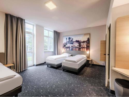a hotel room with two beds and a large window at B&B HOTEL Passau-Süd in Passau