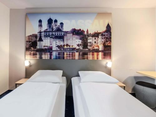 two beds in a room with a picture on the wall at B&B HOTEL Passau-Süd in Passau