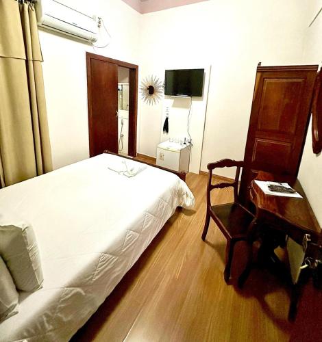 a bedroom with a bed and a desk and a chair at Hotel Lenheiros in São João del Rei