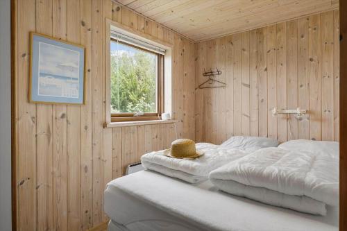 een slaapkamer met houten wanden en een bed met een hoed erop bij JB363-Fjerritslev-Tolderstien-8 in Torup Strand