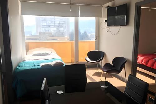 a bedroom with a bed and two chairs and a window at Edificio Barcelona in Temuco