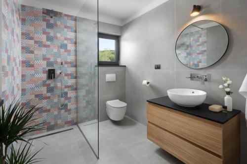 a bathroom with a sink and a toilet and a mirror at Villa Tia in Kukurini - Haus für 8 Personen in Pićan
