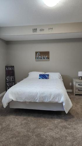 a bedroom with a white bed and a sign on the wall at Oasis at Heritage in Fort McMurray