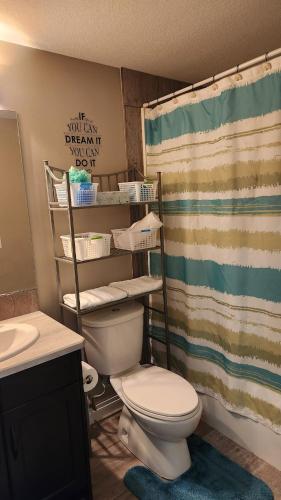 a bathroom with a toilet and a shower curtain at Oasis at Heritage in Fort McMurray