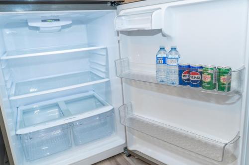 an open refrigerator with soda and water bottles in it at Luxury One Bedroom Private Apartment just 7 minutes from the Airport in Dieppe