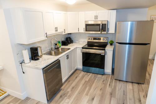 a kitchen with white cabinets and a stainless steel refrigerator at Luxury One Bedroom Private Apartment just 7 minutes from the Airport in Dieppe