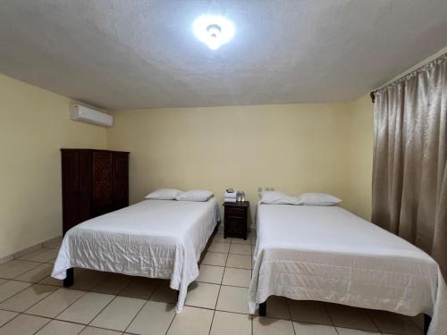 a bedroom with two beds and a light on the ceiling at Hotel y Restaurante Villas Del Sol Jalpan de Serra in Jalpan