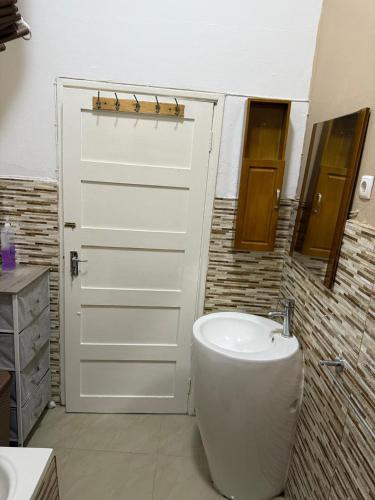 a bathroom with a white door and a sink at House of Peace in Fombeni